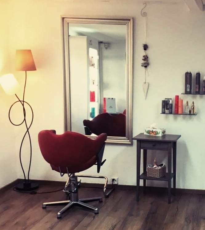 Innenraum des Coiffeursalons mit rotem Stuhl und Spiegel